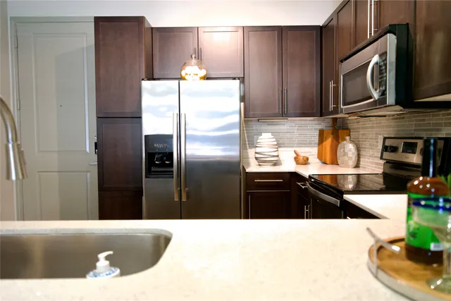 a kitchen with stainless steel appliances kitchen island granite countertop a refrigerator a stove and a sink with wooden floor