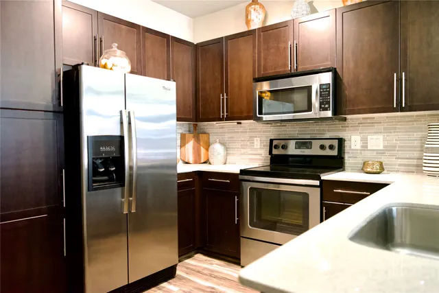 a kitchen with stainless steel appliances kitchen island granite countertop a refrigerator stove and microwave