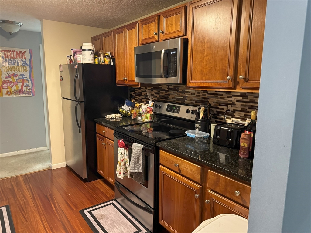 200 Manning Street, Unit 14B Hudson, MA 01749 - Photo 3 of 9 a kitchen with stainless steel appliances granite countertop a refrigerator and a stove top oven