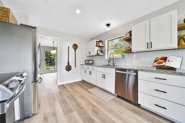 a kitchen with granite countertop a sink stove and cabinets