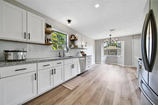 a kitchen with granite countertop a refrigerator sink and cabinets