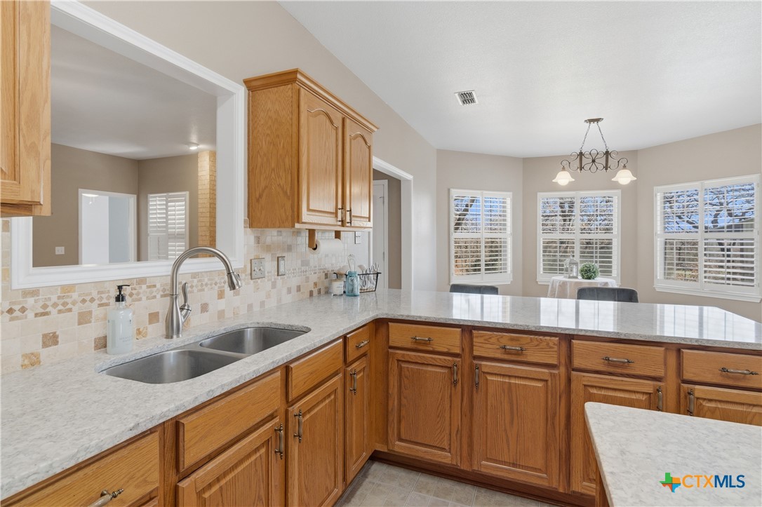 155 Guadalupe Ranch Lane Seguin, TX 78155 - Photo 22 of 48 a large kitchen with kitchen island granite countertop a sink and dishwasher wooden cabinets with a large window
