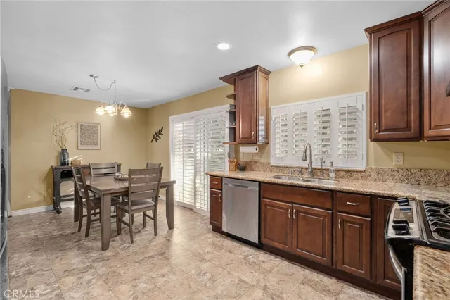 a dining hall with stainless steel appliances granite countertop a stove a sink a dining table and chairs