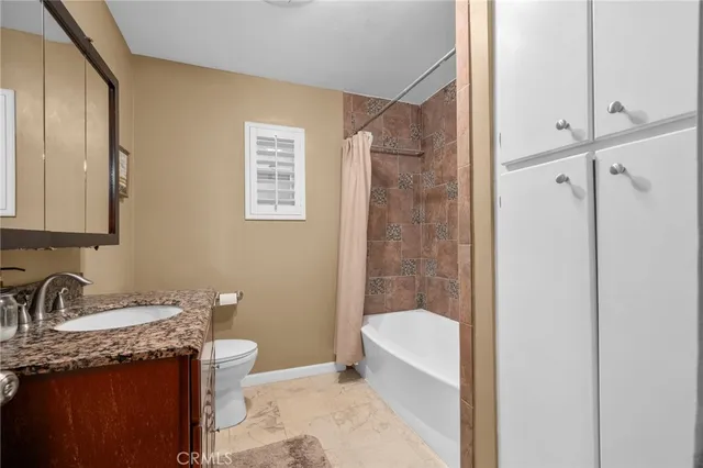 a bathroom with a granite countertop sink a toilet a mirror and shower