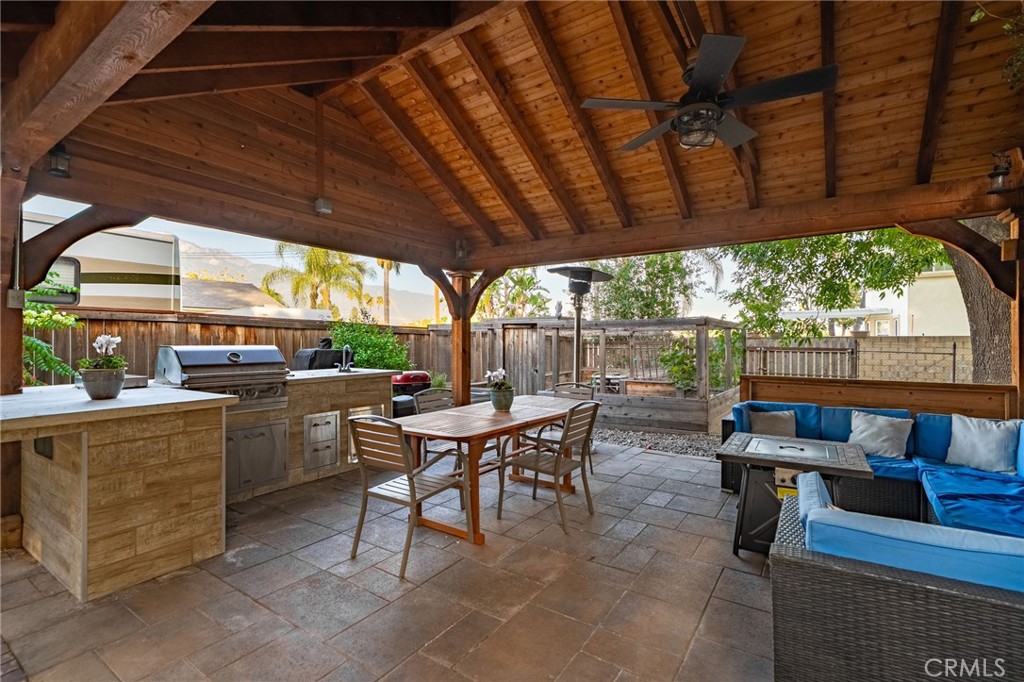 7247 Linden Lane Rancho Cucamonga, CA 91784 - Photo 31 of 51 a view of a patio with a table and chairs under a wooden roof with a barbeque grill with a barbeque grill