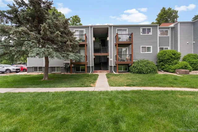 a view of a brick house with a yard and large trees