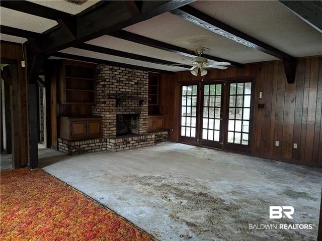 3817 Lansdowne Circle Mobile, AL 36693 - Photo 3 of 16 Unfurnished living room with wooden walls, beam ceiling, ceiling fan, and a fireplace