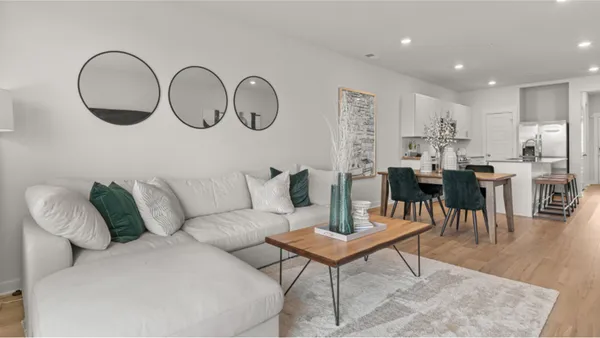 a living room with furniture a rug and kitchen view