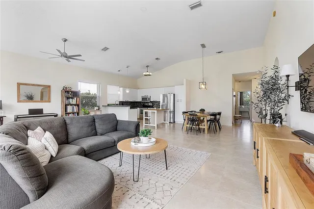 a living room with furniture kitchen view and a potted plant