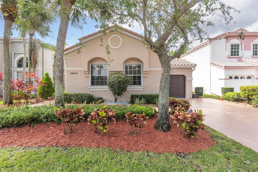 10650 Northwest 48th Street Coral Springs, FL 33076 - Photo 2 of 37 a front view of a house with a garden