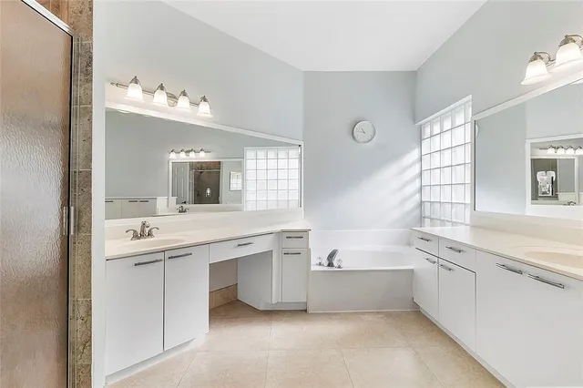 a large white bathroom with a double vanity sink mirror and bathtub