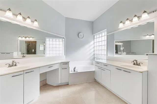 a bathroom with a sink double vanity granite tub and a mirror