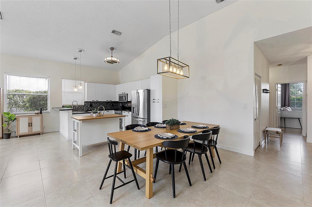 10650 Northwest 48th Street Coral Springs, FL 33076 - Photo 6 of 37 a kitchen with stainless steel appliances kitchen island granite countertop a table chairs sink and cabinets
