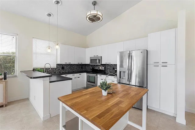 a kitchen with stainless steel appliances granite countertop a table chairs and a refrigerator