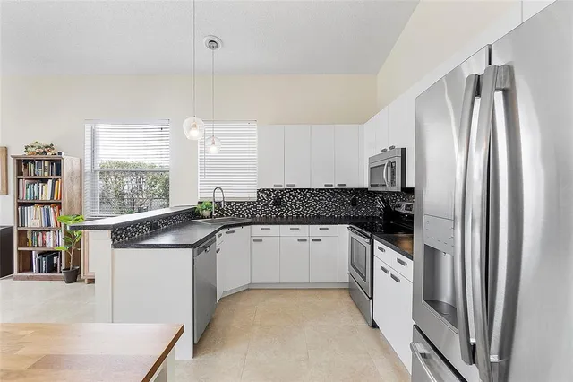 a kitchen with stainless steel appliances granite countertop a sink and a refrigerator