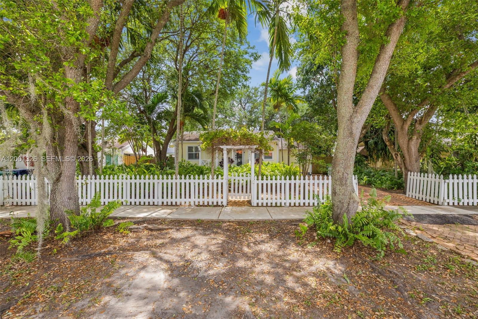a view of a house with a small yard and a large tree