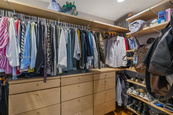 a view of walk in closet with clothes and shoes