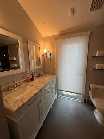 a en suite bathroom with a granite countertop sink and a mirror