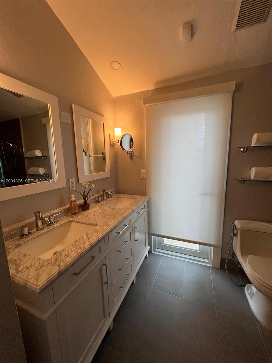 6382 Southwest 38th Street Miami, FL 33155 - Photo 40 of 41 a en suite bathroom with a granite countertop sink and a mirror