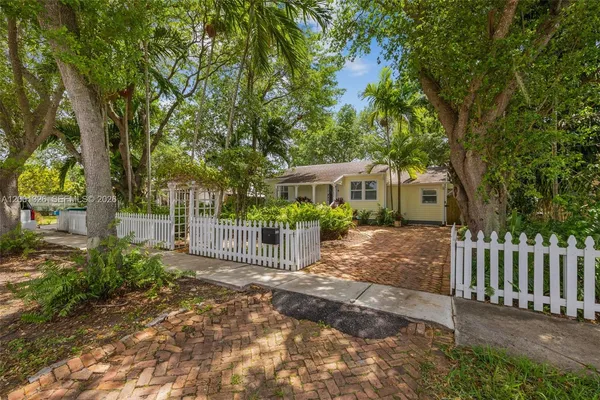 a view of a house with a small yard and a large tree