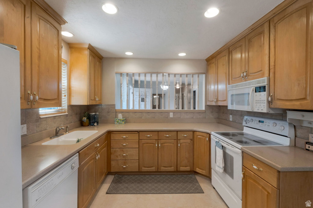 11072 Windy Peak Ridge Drive, Unit 32 Sandy, UT 84094 - Photo 9 of 30 Kitchen featuring extensive wood cabinetry, solid surface countertops, tile backsplash, and recessed lighting