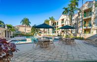 833 Riverside Drive, Unit 835 Coral Springs, FL 33071 - Photo 3 of 25 a view of a patio with dining table and chairs under an umbrella with potted plants