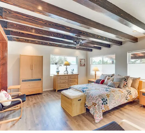 a spacious bedroom with a bed and wooden floor