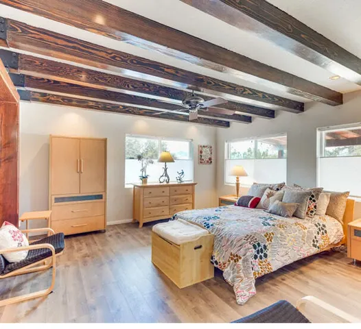 a spacious bedroom with a bed and wooden floor