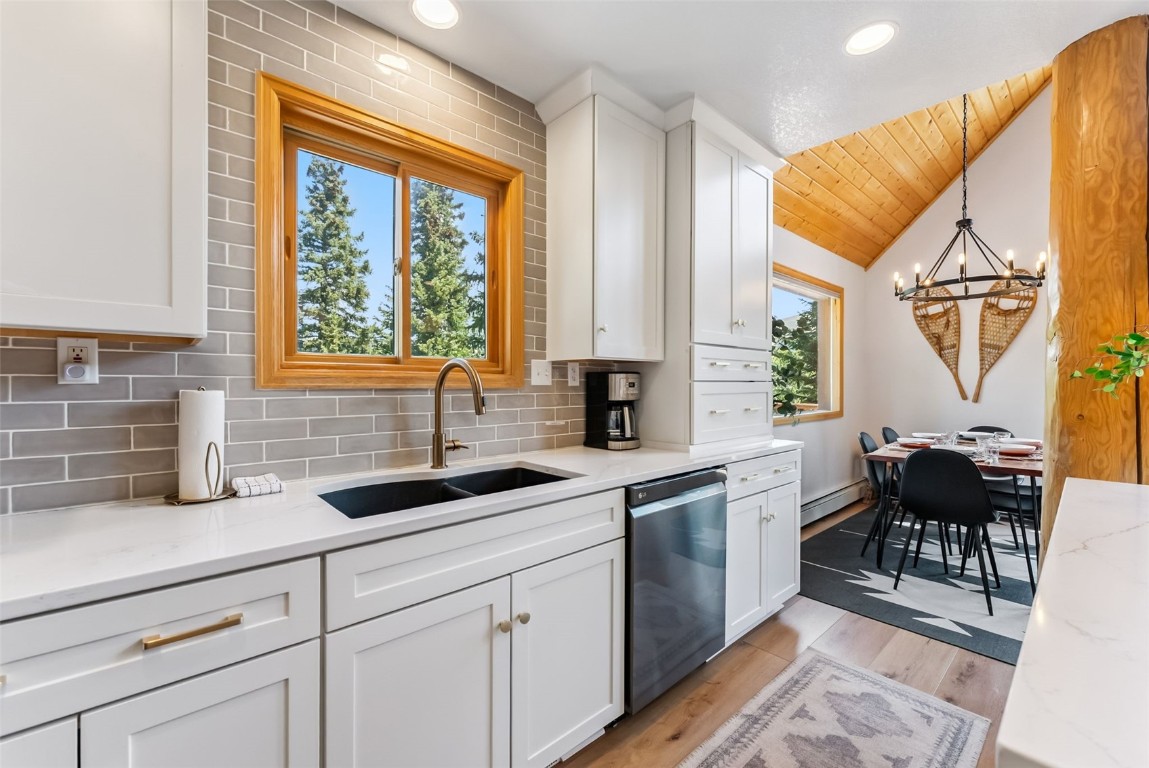1375 Roberts Road Alma, CO 80420 - Photo 11 of 50 Kitchen featuring stainless steel dishwasher, vaulted ceiling, white cabinets, a chandelier, and tasteful backsplash