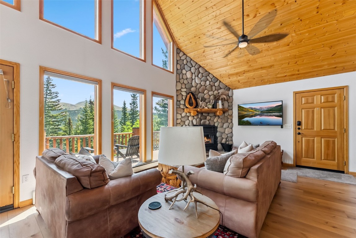 1375 Roberts Road Alma, CO 80420 - Photo 6 of 50 Living area featuring high vaulted ceiling, light wood-style floors, a ceiling fan, wood ceiling, and a stone fireplace