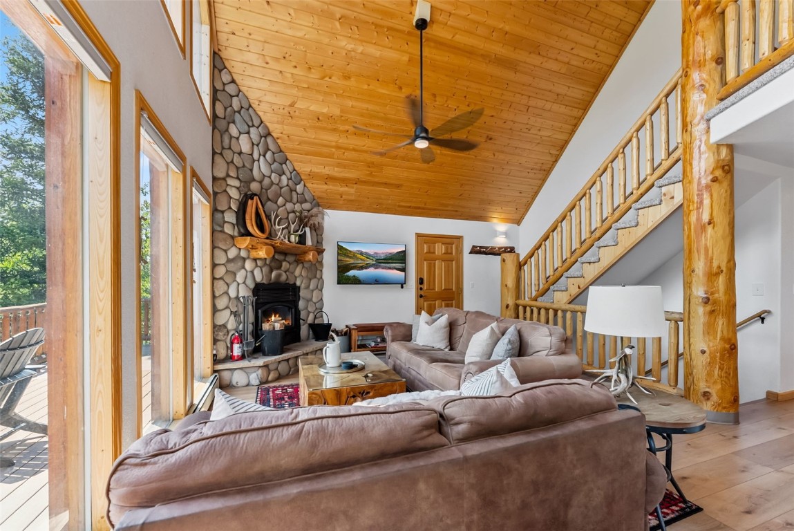 1375 Roberts Road Alma, CO 80420 - Photo 7 of 50 Living room with wood finished floors, ceiling fan, wood ceiling, a stone fireplace, and stairway