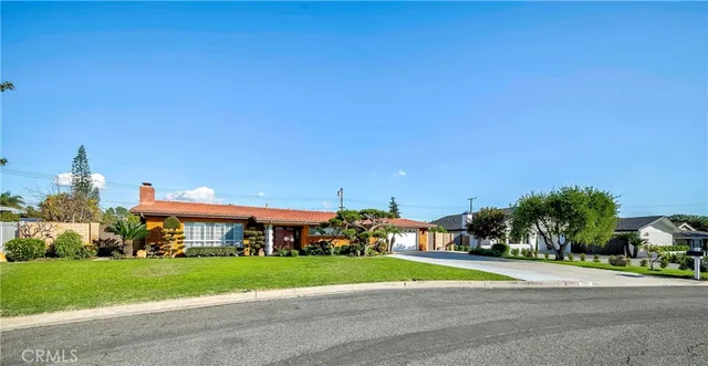 front view of house with a yard and a trees