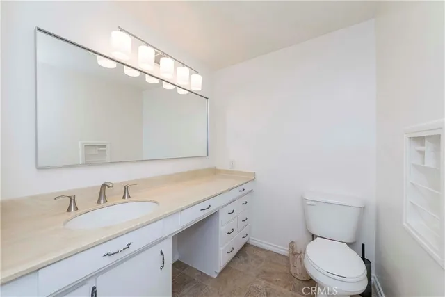 a bathroom with a granite countertop sink a toilet and a mirror