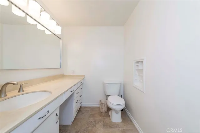 a bathroom with a granite countertop toilet and sink