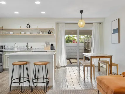 a kitchen with stainless steel appliances granite countertop a table chairs in it and wooden floors