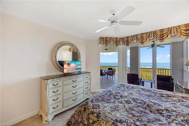 a bedroom with a bed a large window and dresser