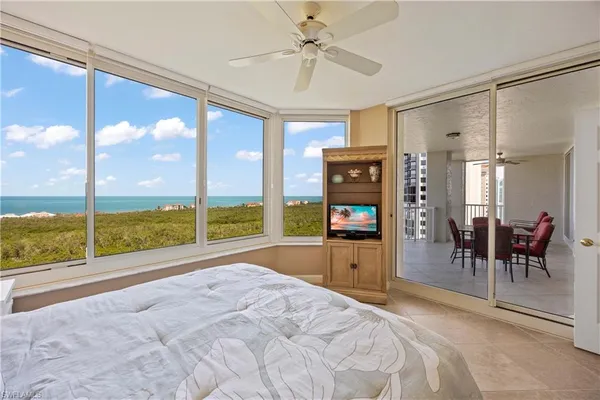 a room with a bed a table and a large window with view of living room