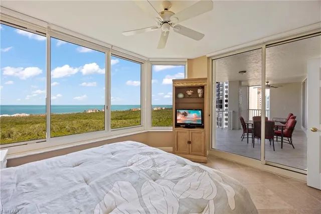 a room with a bed a table and a large window with view of living room