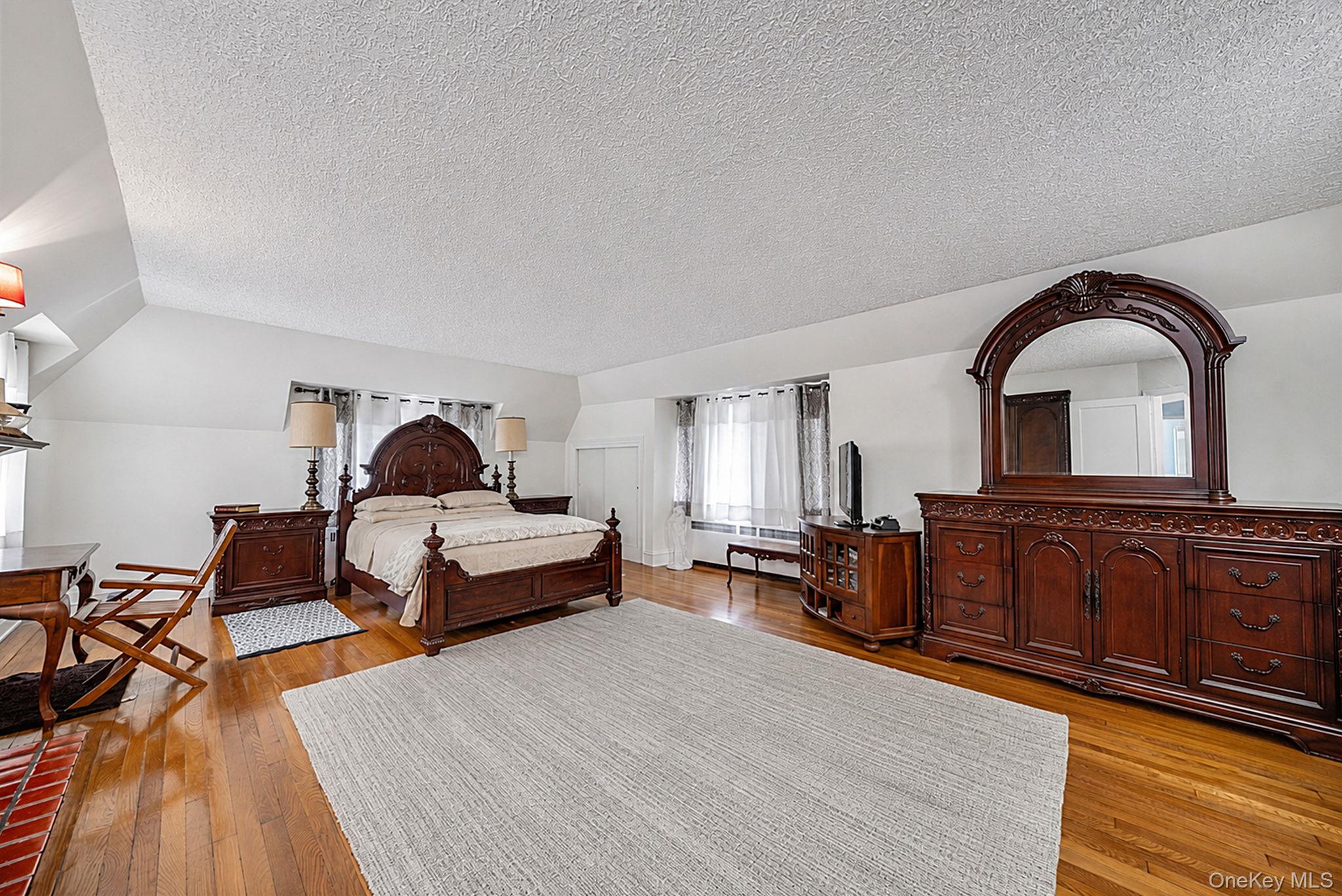18240 Avon Road Queens, NY 11432 - Photo 16 of 30 Spacious room featuring wood-finish flooring, white walls, and a sloped ceiling