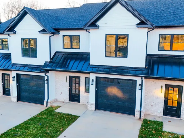 a front view of a house with yard and parking