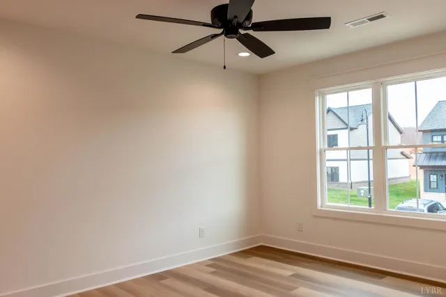 a view of an empty room with a window and wooden floor