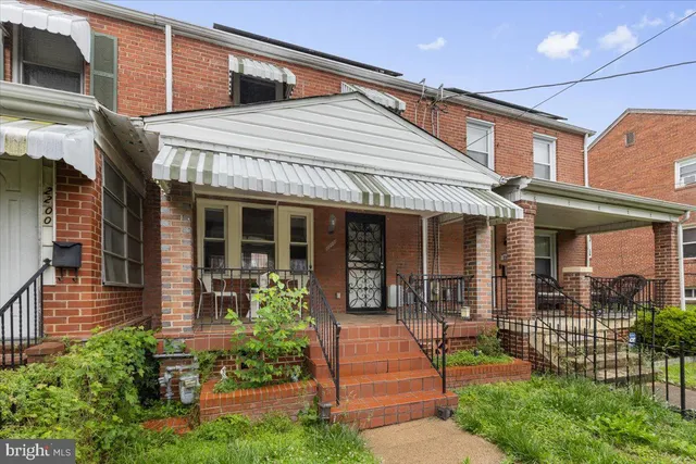 a view of a brick house with plants and large tree