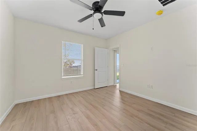 a view of an empty room with window and a ceiling fan