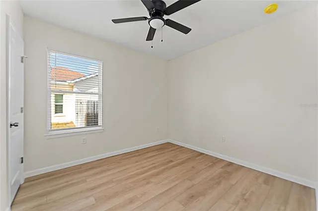 a view of an empty room with a window and a ceiling fan