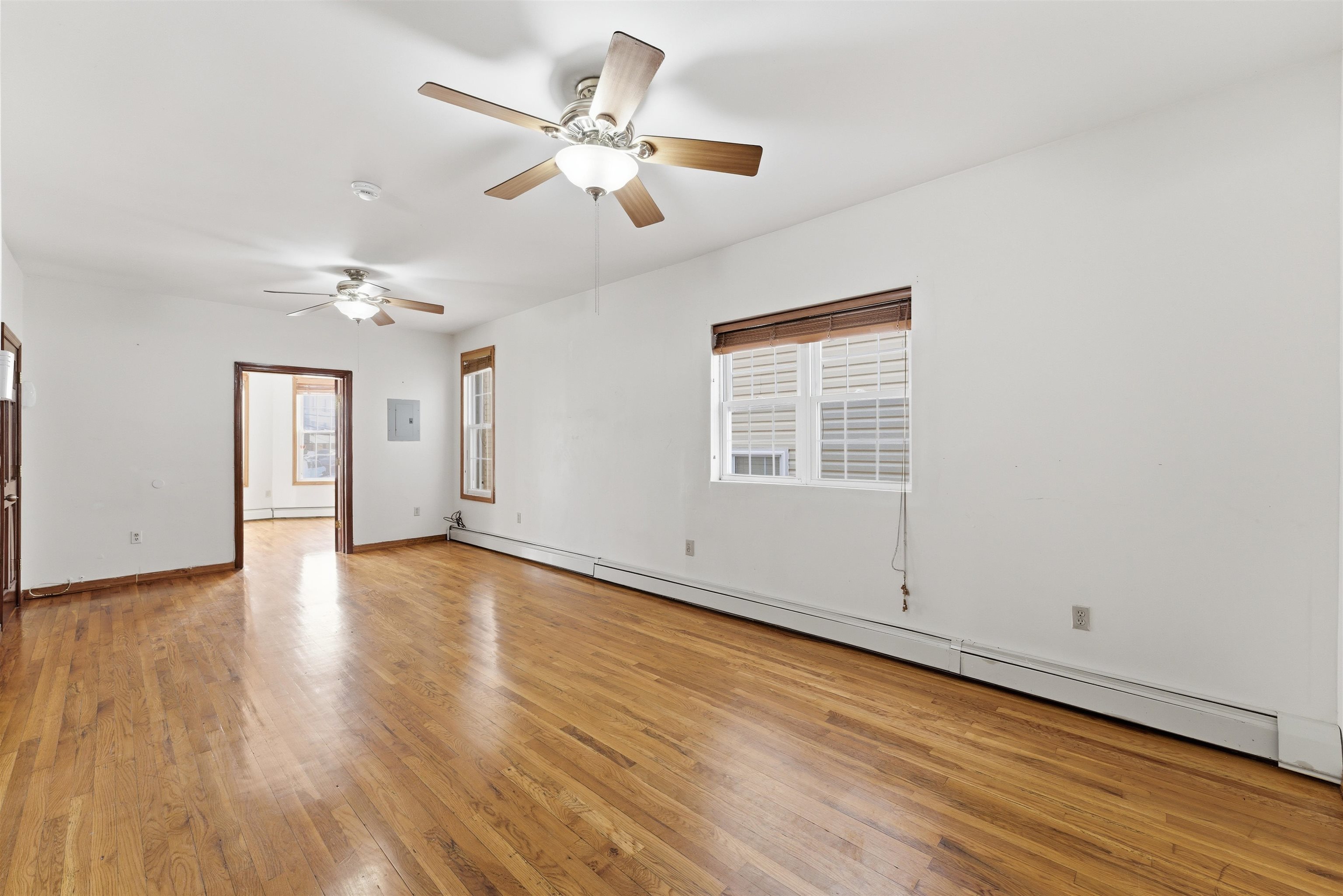 921 Paterson Plank Road North Bergen, NJ 07047 - Photo 10 of 50 an empty room with wooden floor chandelier fan and windows