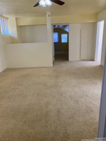 a view of an empty room and chandelier fan