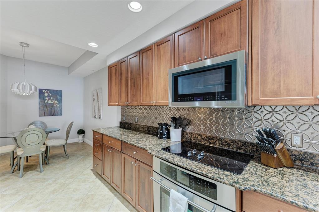 611 Riviera Dunes Way, Unit 304 Palmetto, FL 34221 - Photo 9 of 30 a kitchen with granite countertop wooden cabinets and stainless steel appliances