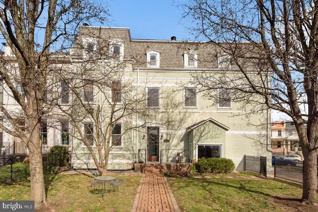 a front view of a building with large trees