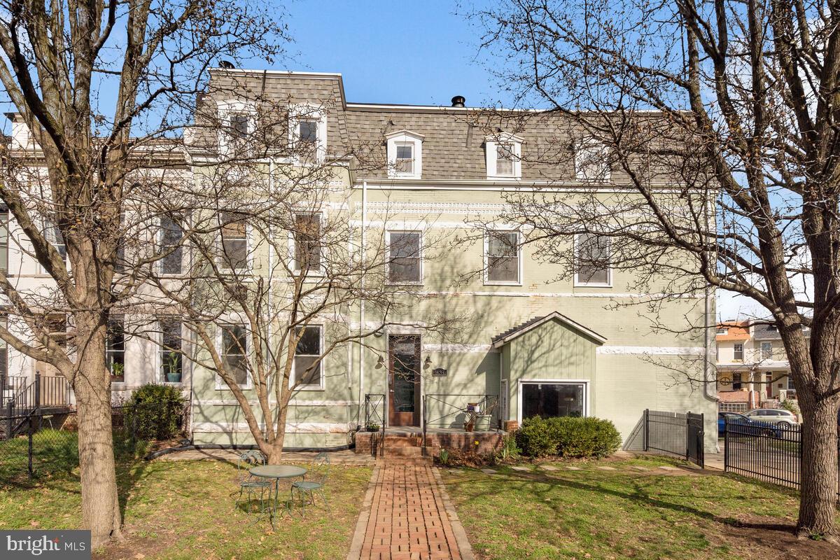 a front view of a building with large trees