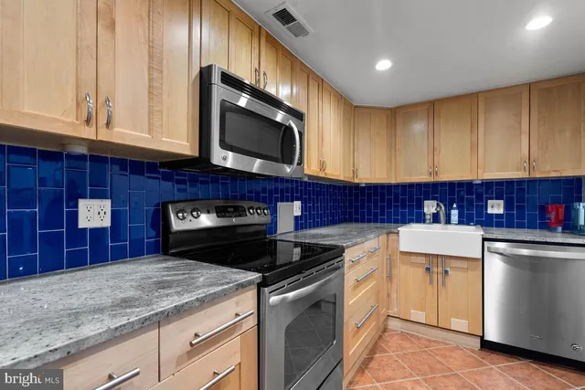 a kitchen with stainless steel appliances granite countertop wooden cabinets a stove and a sink